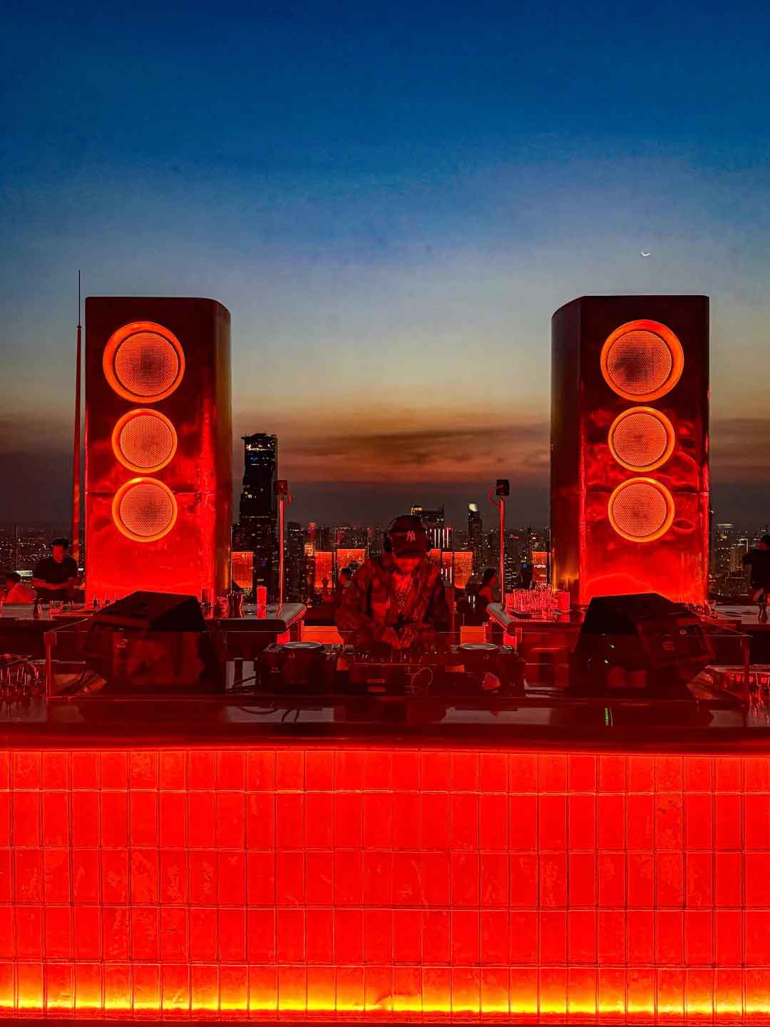 บาร์รูฟท็อป AETHER BKK พร้อมไฟสีส้มและวิวกรุงเทพช่วงหัวค่ำ